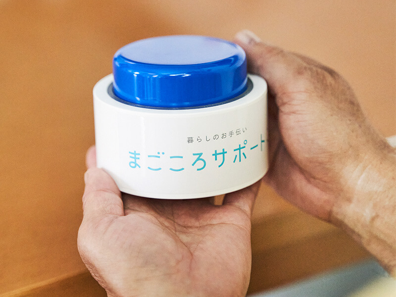 マゴコロボタンを持つシニアの手元アップ